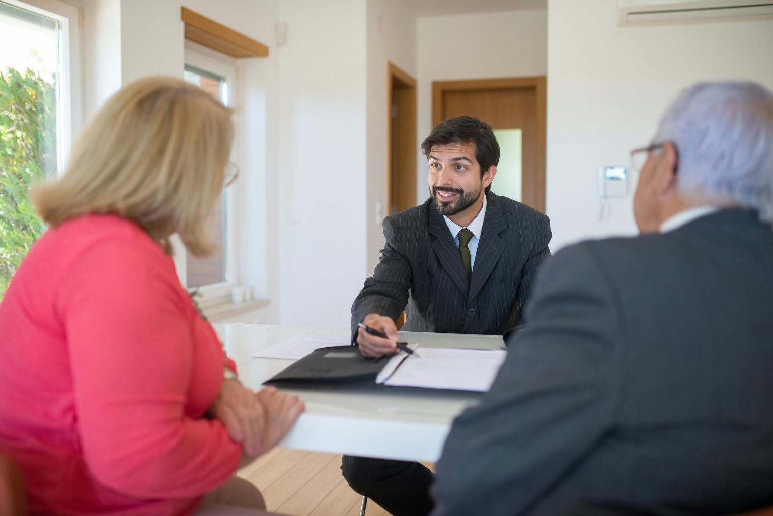 A real estate agent discussing a deal with senior clients in an office setting.